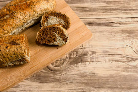 Rye bread cut on cutting board on wooden table.の写真素材