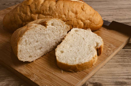White bread cut on cutting board and wooden table.の写真素材