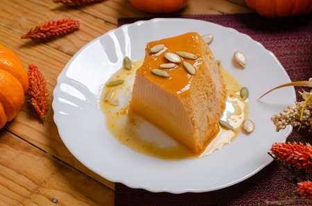 Pumpkin flan, dessert made for the Day of the Dead. Dessert on wooden table with autumn decoration around.の写真素材