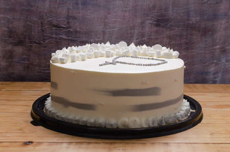 Tres Leches cake made for a christening celebration. Decorated with a rosary at the top. wooden table and abstract background.の写真素材