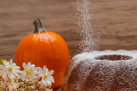 Pumpkin pancake with autumn decoration. Pumpkins and flowers around. Sugar falling on the pancakeの写真素材