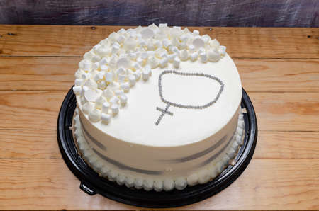 Tres Leches cake made for a christening celebration. Decorated with a rosary at the top. wooden table and abstract background.の写真素材