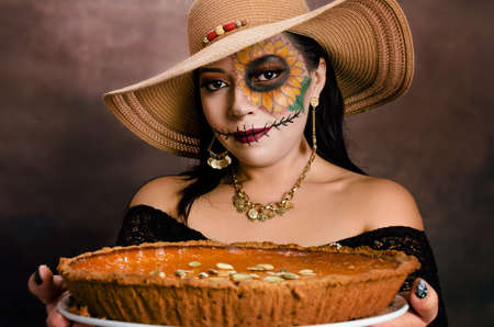 Mexican girl made up as a Catrina offering a traditional Dia de Muertos dessert.の写真素材