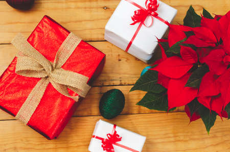 Table with boxes of christmas gifts and pot with poinsettia.の写真素材