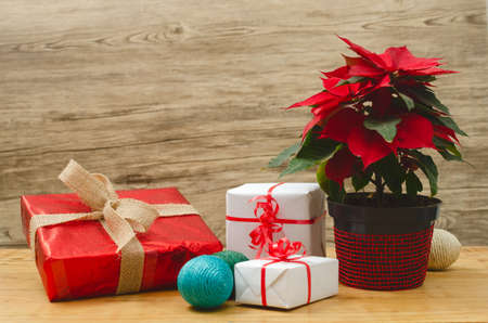 Table with boxes of christmas gifts and pot with poinsettia.の写真素材