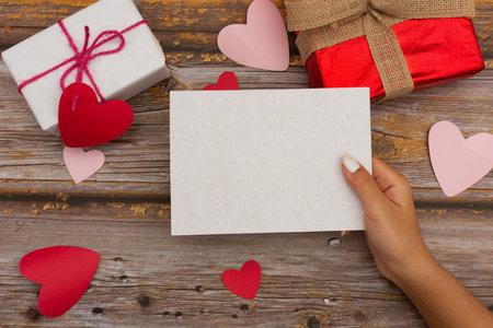 Blank card held by female hand. Table with craft items. Valentines Day card.の写真素材