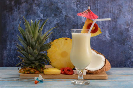 Pina colada, tropical cocktail. Glass of piÃ±a colada on a blue wooden table with the components of the cocktail in the background.の写真素材
