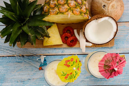 Pina colada, tropical cocktail. Glass of piÃ±a colada on a blue wooden table with the components of the cocktail in the background.の写真素材