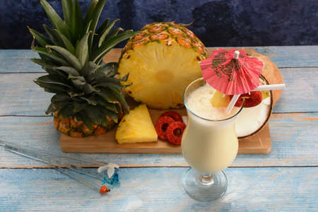 Pina colada, tropical cocktail. Glass of piÃ±a colada on a blue wooden table with the components of the cocktail in the background.の写真素材