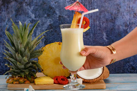 Pina colada, tropical cocktail. Glass of piÃ±a colada on a blue wooden table with the components of the cocktail in the background.の写真素材