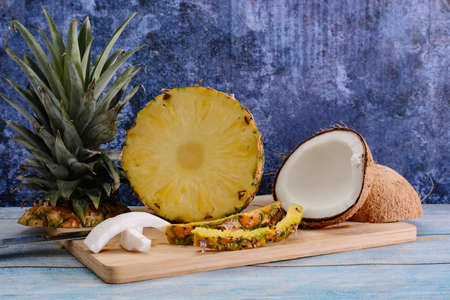 Pina colada, tropical cocktail. Glass of piÃ±a colada on a blue wooden table with the components...