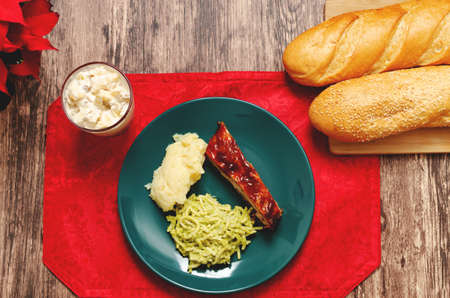 Roasted ribs marinated in barbecue sauce accompanied by mashed potatoes, spaghetti and bread. Plate of food served on wooden tableの写真素材