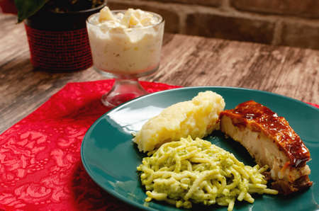Roasted ribs marinated in barbecue sauce accompanied by mashed potatoes, spaghetti and bread. Plate of food served on wooden tableの写真素材