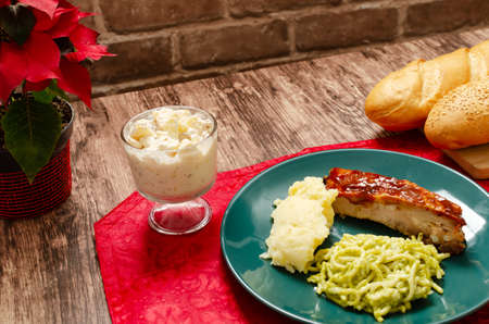 Roasted ribs marinated in barbecue sauce accompanied by mashed potatoes, spaghetti and bread. Plate of food served on wooden tableの写真素材