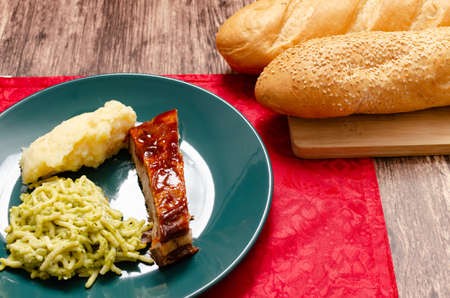 Roasted ribs marinated in barbecue sauce accompanied by mashed potatoes, spaghetti and bread. Plate of food served on wooden tableの写真素材