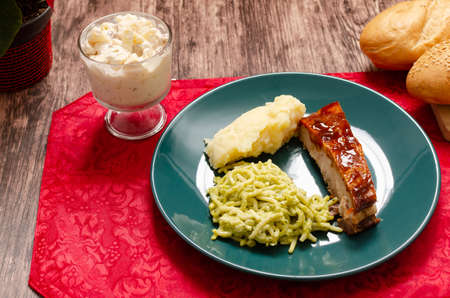 Roasted ribs marinated in barbecue sauce accompanied by mashed potatoes, spaghetti and bread. Plate of food served on wooden tableの写真素材