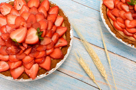 Cheesecake decorated with fresh strawberries on a blue wooden table.