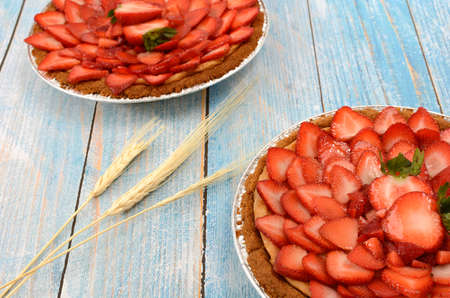 Cheesecake decorated with fresh strawberries on a blue wooden table.の写真素材