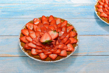 Cheesecake decorated with fresh strawberries on a blue wooden table.の写真素材