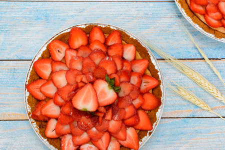 Cheesecake decorated with fresh strawberries on a blue wooden table.の写真素材
