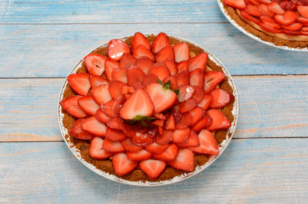 Cheesecake decorated with fresh strawberries on a blue wooden table.の写真素材