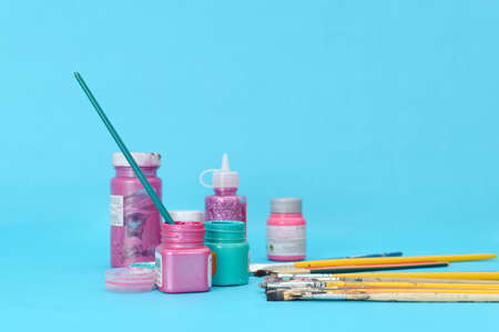 Group of used brushes and paint pots on blue background.の写真素材