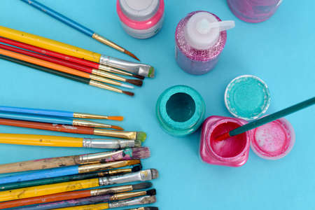 Group of used brushes and paint pots on blue background.の写真素材