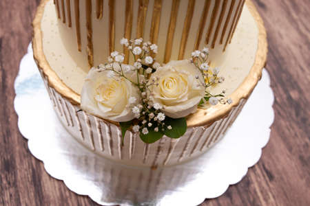 Cake decorated with natural roses. Beautiful wedding cake decorated with roses on wooden table.