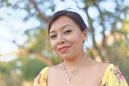 Outdoor portrait of woman in yellow dress. Mexican woman walking in a park enjoying nature.の写真素材