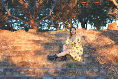 Outdoor portrait of woman in yellow dress. Mexican woman walking in a park enjoying nature.