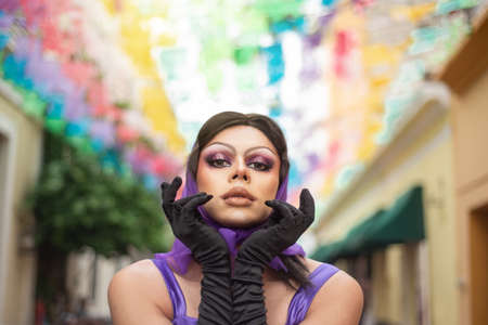 Drag queen street portrait with multicolored background. Young man dressed as a woman looking at the camera.の写真素材