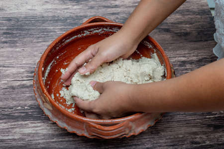 Woman's hands mixing corn dough to make tortillas. Mexican basic food.