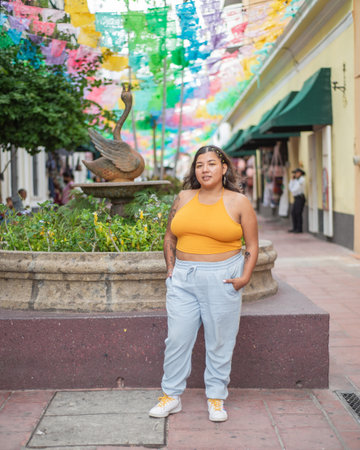 Street portrait of young woman looking at camera with multicolored flags in background.の写真素材
