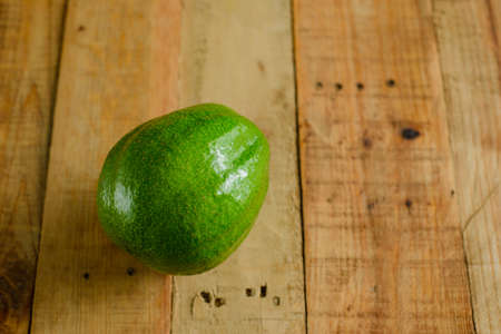 Avocado on wooden table. Isolated avocado in foreground.