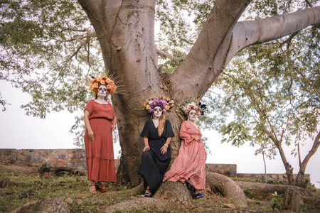 Group portrait of three women with the makeup of the catrinas.. Makeup for the celebration of Day of...