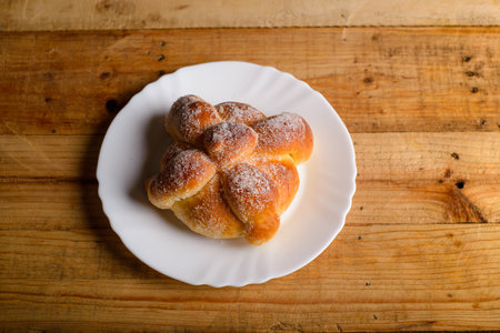 Pan de muerto on a white plate isolated on a wooden table. Typical mexican dessert.の写真素材