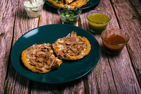 Sope pocho, typical Mexican food served with condiments on a wooden table.の写真素材