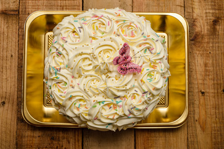 Cake decorated with butter cream flowers on a wooden table.