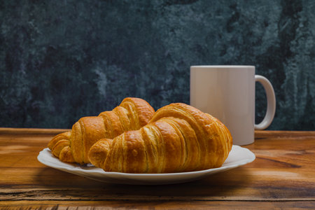 Croissants in white plate on wooden table. Side view.の写真素材