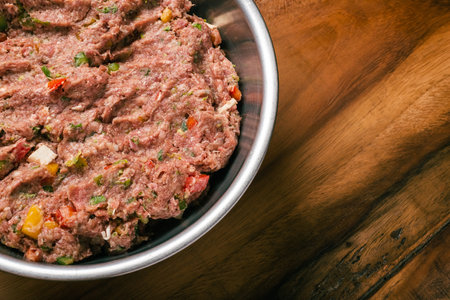 Ground meat dough prepared for homemade hamburger. Ground meat in metal bowl on wooden table.の写真素材