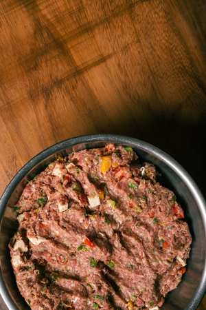 Ground meat dough prepared for homemade hamburger. Ground meat in metal bowl on wooden table.