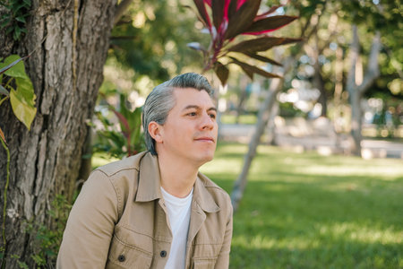 Portrait of gray-haired adult male with positive expression sitting in a park.の写真素材