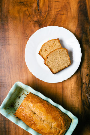 Homemade sponge cake in blue ceramic mold on wooden table. Sliced pound cake.の写真素材