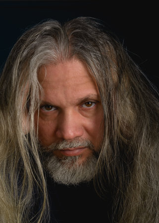 Close-up portrait of man with beard and gray hair. Looking at camera.