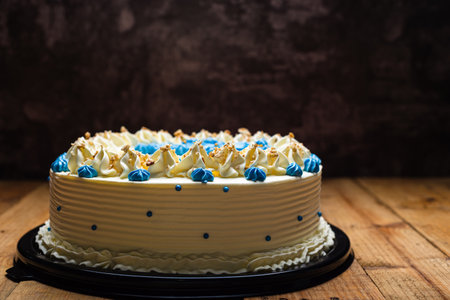 Cake decorated with blue cream cheese flowers and cracked walnut. Cake on wooden table.の写真素材