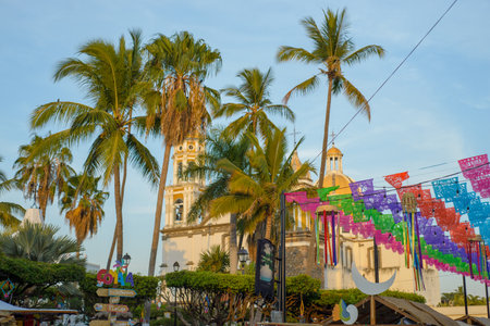 Eat it, Colima. Mexico. April 01, 2023. Comala Cathedral seen through palms during the Bread, Punch and Coffee Fair.のeditorial素材