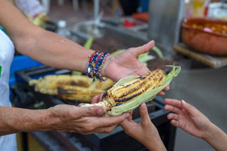 Person selling charcoal-grilled elote (corn). Mexican street food