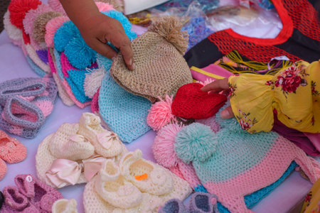 Baby hats and slippers knitted with worsted yarn. Colorful knits in a street market.の写真素材