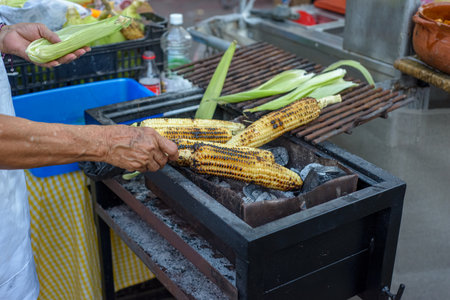 Person selling charcoal-grilled elote (corn). Mexican street foodの写真素材