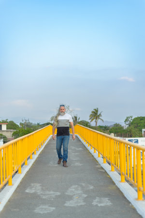 Long-haired gray-haired man on a pedestrian bridge.の写真素材